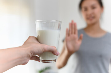 Woman gesturing refusing stop or reject say no glass of milk, Lactose intolerance food allergy and...