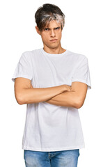 Young hispanic man wearing casual white tshirt skeptic and nervous, disapproving expression on face with crossed arms. negative person.