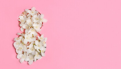 Fototapeta premium White flowers in the shape of the number eight on a pink background. International Women's Day. Postcard for March 8. Banner, flyer. Copy space.