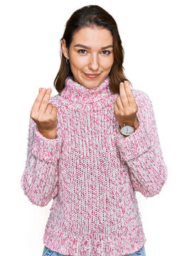 Young caucasian girl wearing wool winter sweater doing money gesture with hands, asking for salary payment, millionaire business