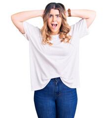 Young caucasian woman wearing casual clothes crazy and scared with hands on head, afraid and surprised of shock with open mouth