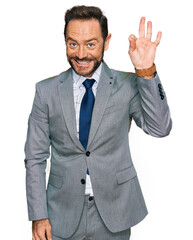 Middle age man wearing business clothes smiling positive doing ok sign with hand and fingers. successful expression.