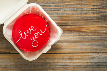 Red bento cake in Korean style with I love you inscription on wooden background, top view,...