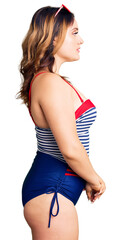 Young beautiful caucasian woman wearing swimwear looking to side, relax profile pose with natural face with confident smile.