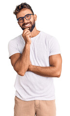 Young hispanic man wearing casual clothes and glasses looking confident at the camera smiling with...