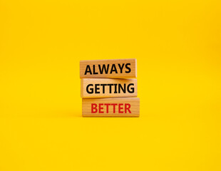 Always getting better symbol. Wooden blocks with words Always getting better. Beautiful yellow background. Business and Always getting better concept. Copy space.