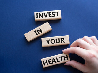 Invest in your Health symbol. Concept words Invest in your Health on wooden blocks. Businessman hand. Beautiful deep blue background. Business and Invest in your Health concept. Copy space.