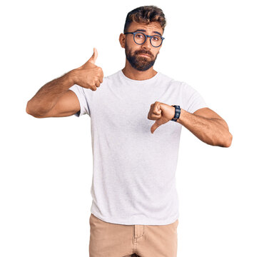 Young hispanic man wearing casual clothes and glasses doing thumbs up and down, disagreement and agreement expression. crazy conflict