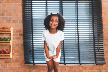 A portrait or close up of an African American little girl smiling and happy, cute and pretty lively and lovely girl with attractive and innocence looking, playful and joyful, positive and carefree.