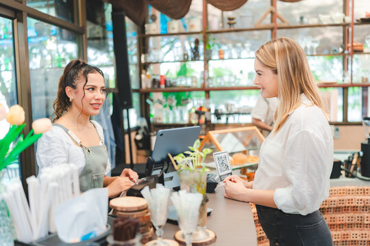 Female customer order food ,drinks or coffee with Female Barista, waitress or cashier at a coffee shop or café counter bar. Small business entrepreneur receive order and having a positive conversation