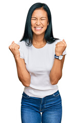 Beautiful hispanic woman wearing casual white tshirt excited for success with arms raised and eyes closed celebrating victory smiling. winner concept.