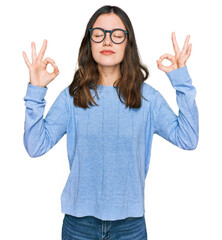Young beautiful woman wearing casual clothes and glasses relaxed and smiling with eyes closed doing meditation gesture with fingers. yoga concept.