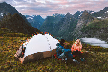 Couple man and woman traveling together with camping tent gear romantic vacations friends hiking adventure outdoor family healthy lifestyle climbing mountains of Norway Valentines day holiday - obrazy, fototapety, plakaty