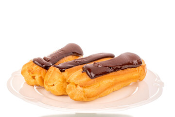 Three sweet chocolate eclairs on a white ceramic dish, close-up, isolated on a white background.