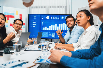 Analyst team utilizing BI Fintech to analyze financial data at table in meeting room. Businesspeople analyzing BI dashboard power for business insight and strategic marketing planning. Prudent