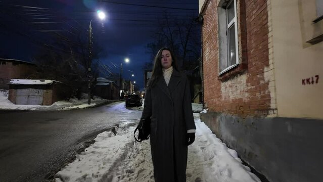 Woman walking in winter at night in the city. 