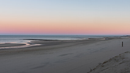 The beach of North Holland (Netherlands) looks deserted on this morning. The rising sun creates beautiful pastel colors.