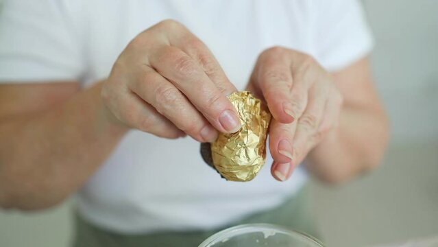 Female hands opening a pack of chocolate candy and bites a piece of candy, enjoying the taste. High quality FullHD footage