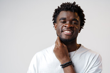 Obraz premium Portrait of a smiling young african man wearing white t-shirt standing over gray background