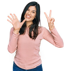 Young hispanic woman wearing casual clothes showing and pointing up with fingers number seven while smiling confident and happy.