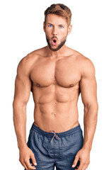Young caucasian man standing shirtless afraid and shocked with surprise expression, fear and excited face.