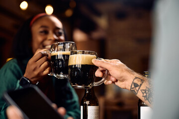 Close up of couple toasting with beer in pub.