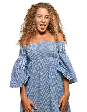 Beautiful caucasian teenager girl wearing summer dress sticking tongue out happy with funny expression. emotion concept.