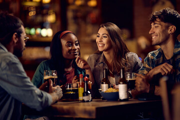 Group of happy friends communicating while enjoying their night out in bar.