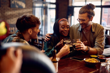 Happy friends toasting while drinking beer in pub.