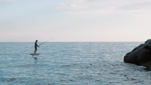 Two young active persons riding on electric hydrofoil surfboards on ocean water