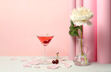 Modern still life with pink martini, alcoholic cocktail, cherry berries and peony flowers on...