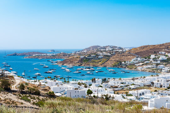 Mikonos, Greece - Ornos Beach. With umbrella and luxury beach chairs beds in front of blue ocean, Ornos is a family beach with crystal and shallow water.