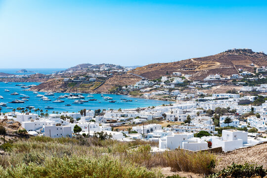 Mikonos, Greece - Ornos Beach. With umbrella and luxury beach chairs beds in front of blue ocean, Ornos is a family beach with crystal and shallow water.