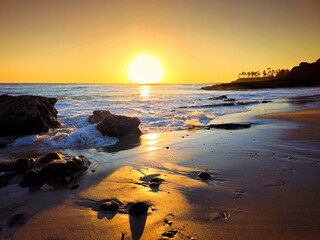 Sunset over the Pacific Ocean at  Laguna Beach with footsteps in the sand, California, USA