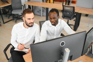 Two confident businessmen, financial analysts or investment advisers sitting at office desk