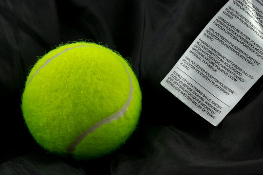 Tennis balls and clothing label on black jacket. Garment label with instructions for drying clothing.   Bouncing tennis balls help loosen and fluff up the down or other padding inside the jacket. 