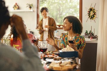 Happy friends enjoying in conversation and drinking wine during festive dinner at home party