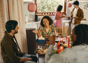Happy friends enjoying in conversation and drinking wine during festive dinner at home party