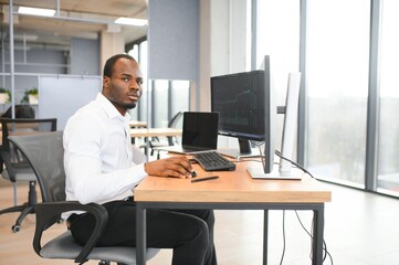 African-American broker works in office using workstation and analysis technology