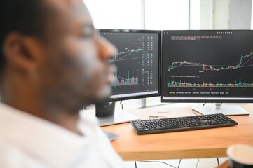 African-American broker works in office using workstation and analysis technology