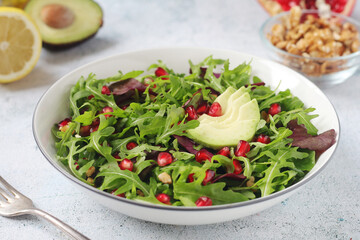 A plate with green rocket salad with pomegranate and avocado