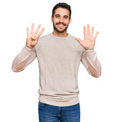 Young hispanic man wearing casual clothes showing and pointing up with fingers number nine while smiling confident and happy.