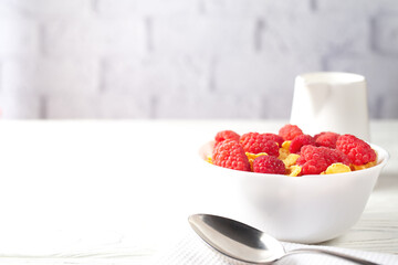 Delicious corn flakes with raspberries on a white wooden background. Fresh healthy food.