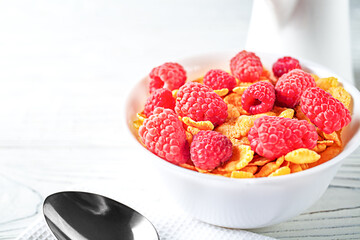 Delicious corn flakes with raspberries on a white wooden background. Fresh healthy food.