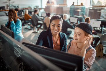 Two young women working together on a computer in college library