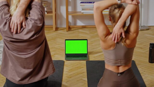 Spouse using laptop with green screen during home workout
