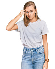 Fototapeta premium Beautiful young blonde woman wearing casual white t shirt pointing unhappy to pimple on forehead, ugly infection of blackhead. acne and skin problem