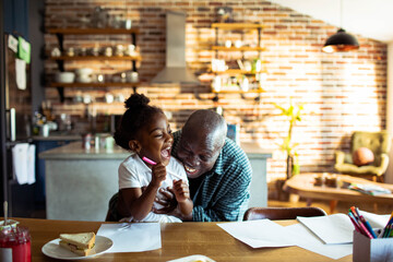 Grandfather laughing with granddaughter in kitchen - obrazy, fototapety, plakaty