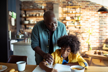 Grandfather doing homework with grandson at home - obrazy, fototapety, plakaty
