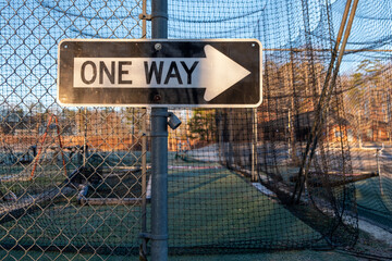 One way sign on a metal fence.